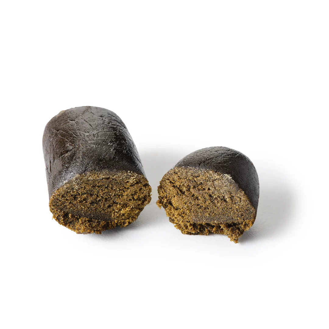 Beldia | CBD + CBG Hash | PureBotanica | 21 % CBD Nahaufnahme eines halbierten Stücks dunkelbraunen CBD-Haschischs mit weicher, dichter Innenstruktur auf weißem Hintergrund – Premium Vollspektrum-CBD-Hasch von Pure Botanica.
